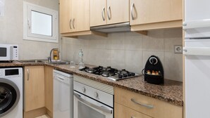 A kitchen with wooden cabinets, a gas stove, a microwave, and a dishwasher. - Flateli. PDA Vista Mar 3 (Platja d´Aro)