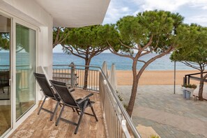Varanda com duas cadeiras, guarda-corpo e vista para a praia e o mar.