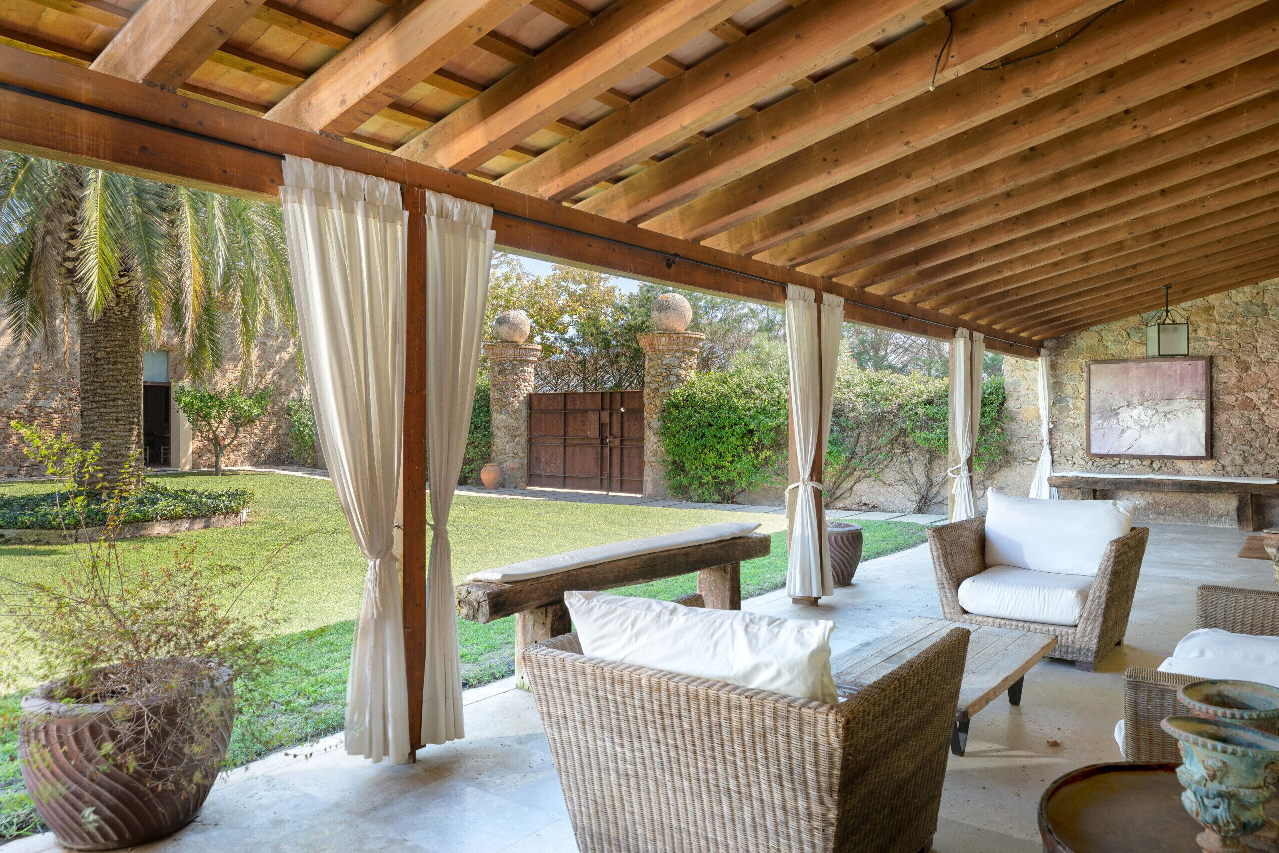 Un espace extérieur aménagé en terrasse, avec des meubles en osier, une cheminée en pierre et une vue sur le jardin.