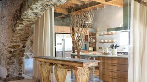 Eine rustikale Küche mit Steinwand, Holzschränken und einer zentralen Kochinsel mit einer Holzskulptur.