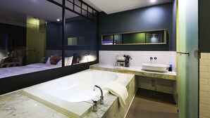 A modern bathroom with a large bathtub, a separate sink, and a mirror above the sink. - Desing Hotel Vine (Ansan)