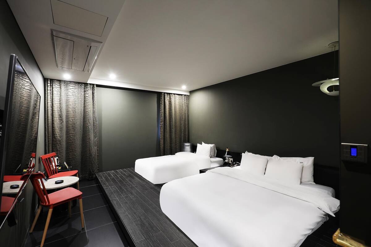 A modern hotel room with two beds, a desk, and a chair.