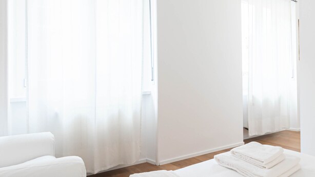 A hotel room with a large bed, a chair, and a stack of towels. - Italianway Comfort - Salmini 1 (Milan)