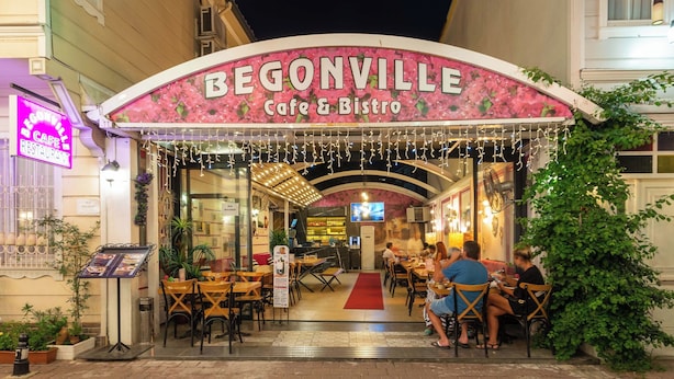 Ein Café namens 'Begonville' mit Außenplätzen und einem roten Teppich, der zum Eingang führt.