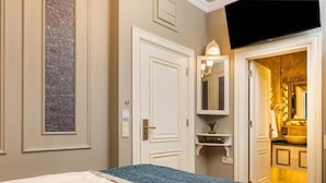 Ein Hotelzimmer mit einem Bett, einer Tür, einem Spiegel, einem Regal und einem sichtbaren Badezimmer durch eine geöffnete Tür.