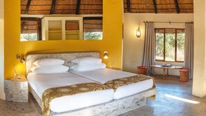 A spacious bedroom with a large bed, a small table, and a window with curtains.