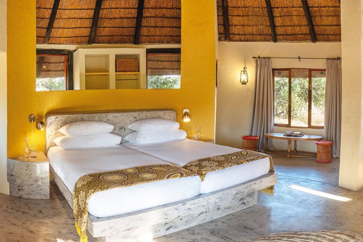 A spacious bedroom with a large bed, a small table, and a window with curtains.