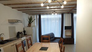 Cozinha compacta com mesa e cadeiras, máquina de lavar e um pequeno frigorífico.