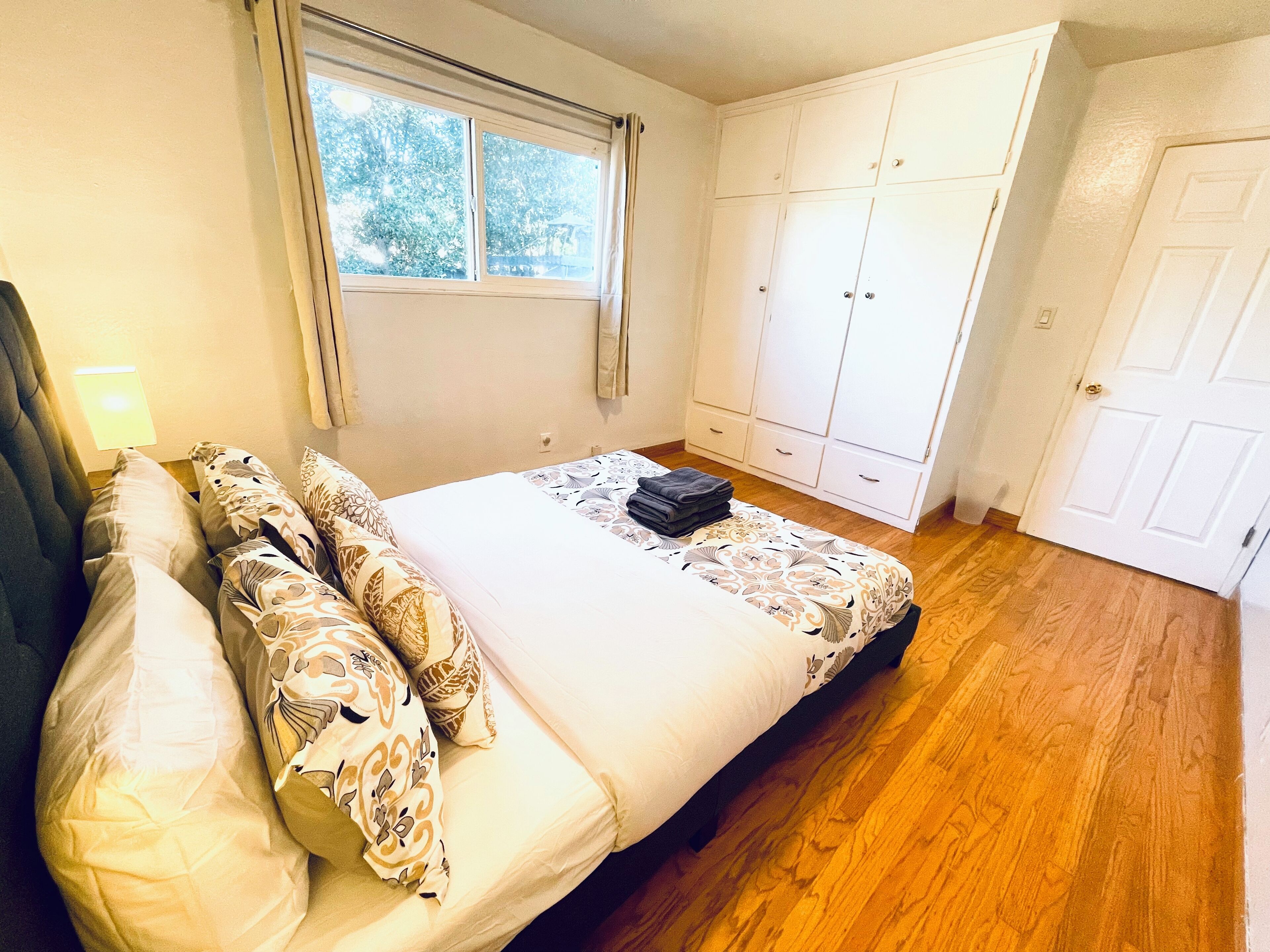 A bedroom with a bed, a window, a wardrobe, and a door.
