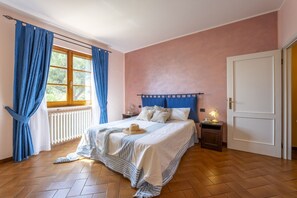 Cozy retreat with a large bed against a window, a nightstand, and a small table.