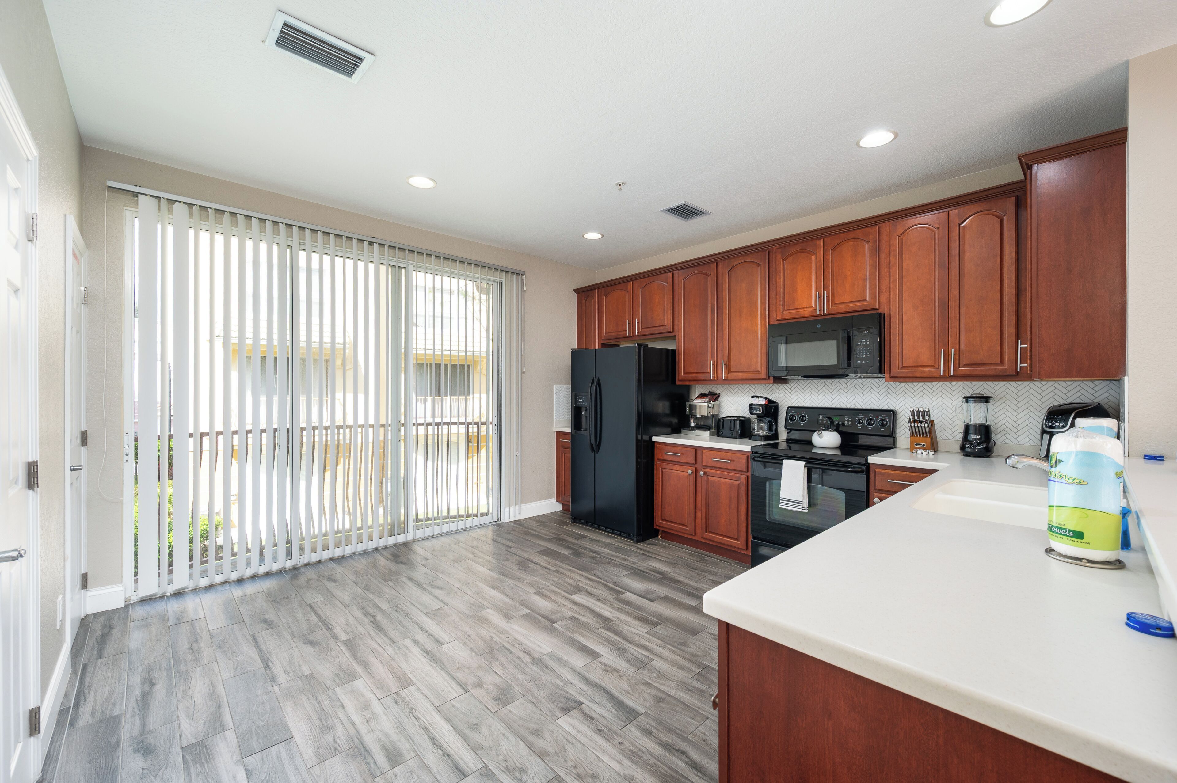 A modern kitchen with wooden cabinets, a black refrigerator, a microwave, and a coffee maker.