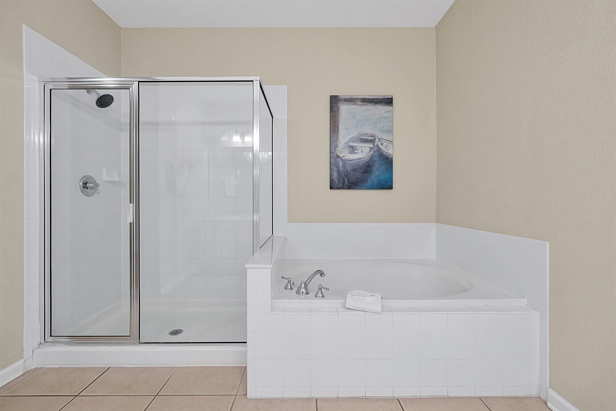 A bathroom with a glass-enclosed shower, a white bathtub, and a beige wall.