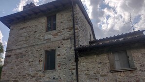 A stone building with two windows, a door, and a small balcony. - Apartment in Farmhouse (Pelago)