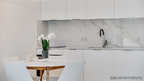A modern kitchen with white cabinetry, a marble backsplash, and a dining area with a white table and chairs. - Luxury Apt • AC • Workspace • 5 min to Downtown (Kraków)