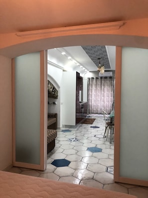 Een modern interieur met een zeshoekig betegelde vloer, een eethoek met een kroonluchter, en een keuken met een stenen boog.
