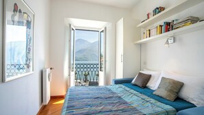 Un dormitorio con una cama, una estantería y vistas a las montañas desde una puerta abierta.