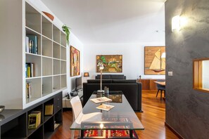 A modern living room with a glass dining table, a bookshelf, a sofa, and a painting on the wall. - Piazzetta Lake View, Lovely 2 Br Flat With Gorgeous View By Halldis (Dongo)