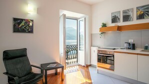 Una cocina moderna con horno integrado, un comedor con una silla y mesa, y un balcón con vistas a las montañas.