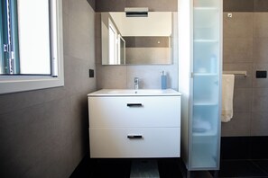 A modern bathroom with a white vanity, a mirror, and a glass shower enclosure.