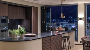 Eine moderne Küche mit einer großen Kochinsel, dunklen Holzschränken und Blick auf die nächtliche Stadt.