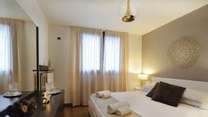 Ein Hotelzimmer mit Bett, Nachttisch, Lampe, Vorhängen und einem Wanddekor.