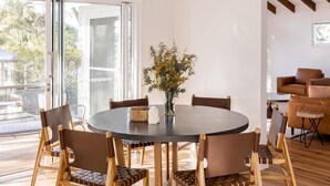 Un coin repas avec une table ronde, six chaises et un vase de fleurs.