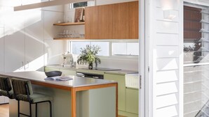 Une cuisine moderne avec des meubles en bois, un îlot central et un coin repas équipé d’une chaise.