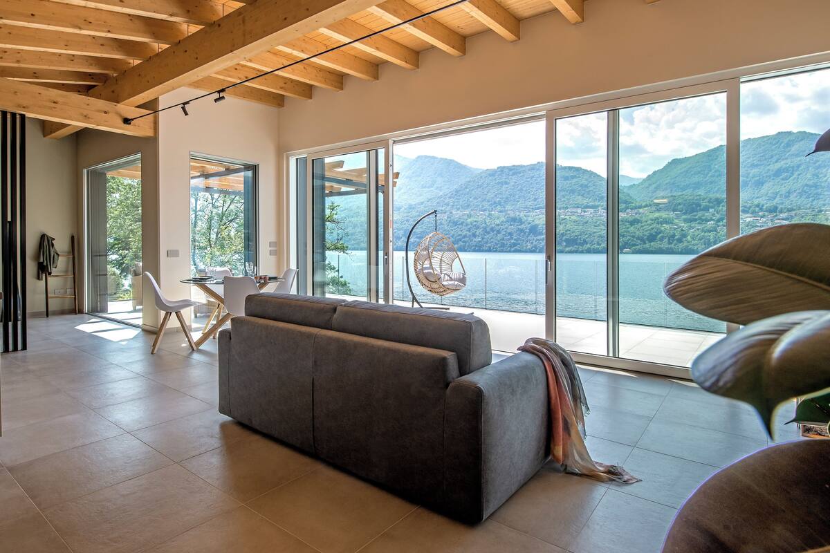 A spacious living area with a large gray sofa, a hanging chair, and a dining table.