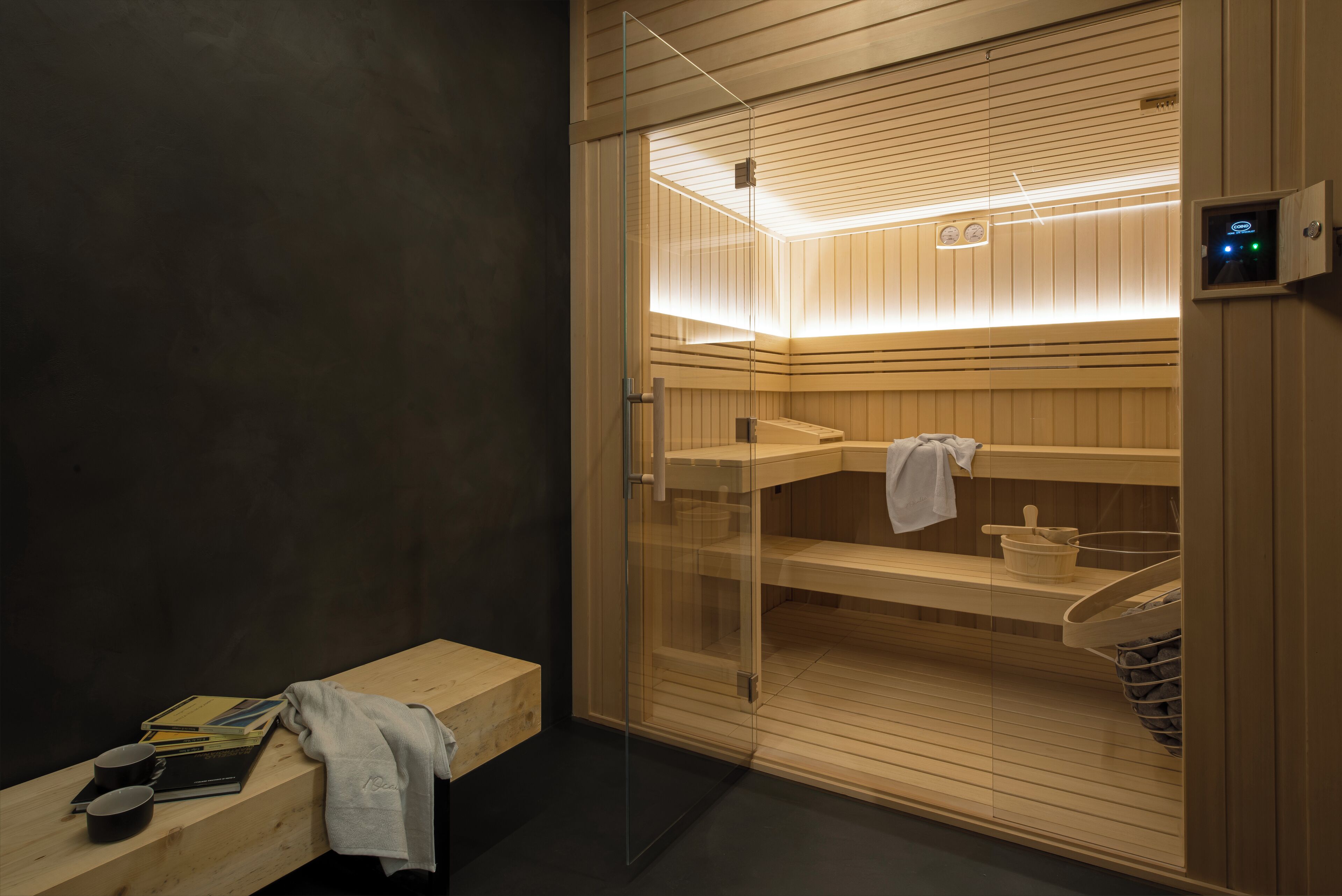 En sauna med træbænke, glasdør og et håndklædeholder.