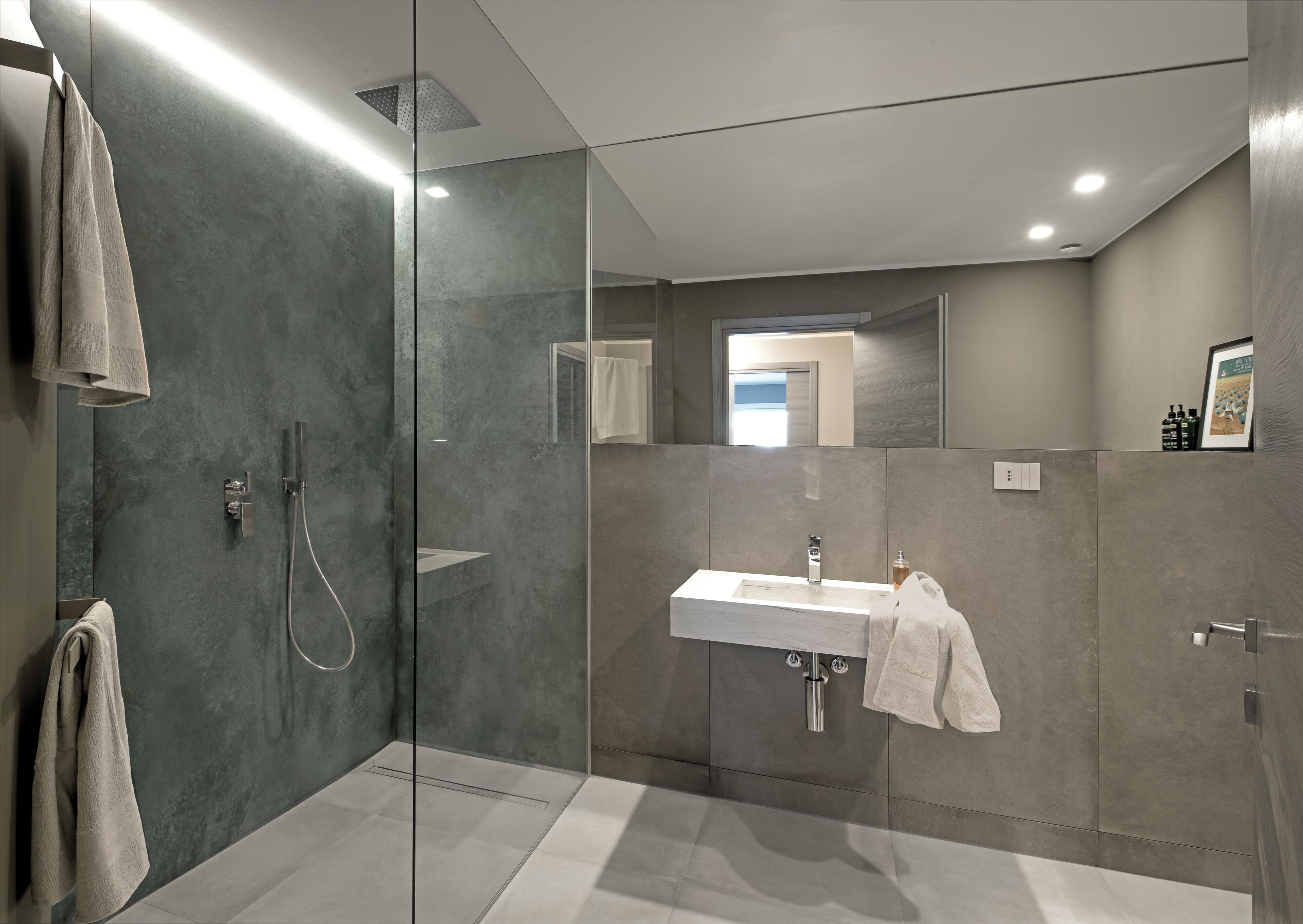 A modern bathroom with a glass-enclosed shower, a vanity with a sink, and a towel rack.