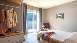 A hotel room with a bed, a desk, a chair, and a view of a body of water. - d'Ocalée Holiday Experience (Omegna)