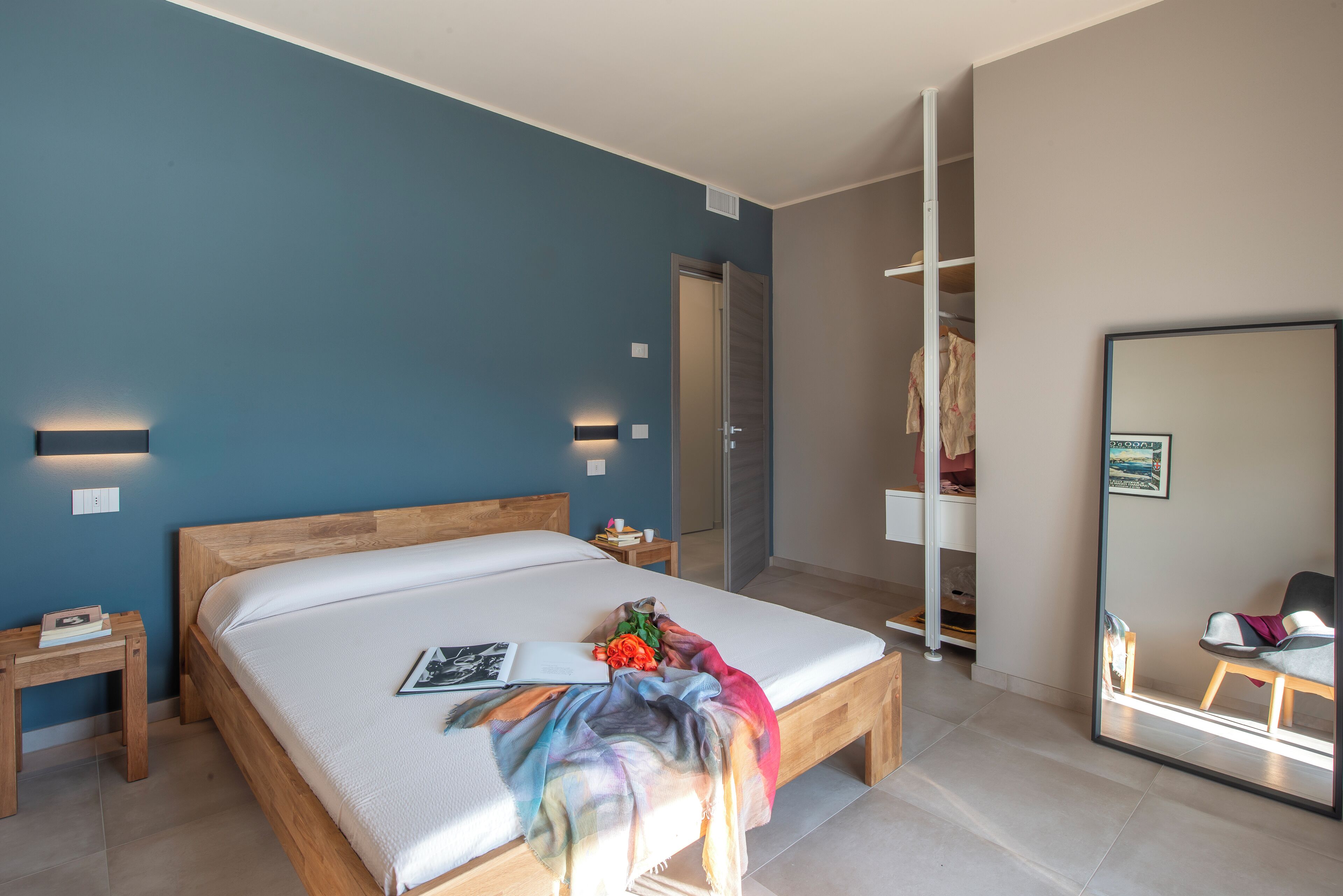 Un dormitorio con cama de madera, una mesita de noche, un tocador, un espejo y un armario.