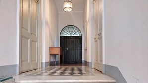A hallway with a checkered floor, a wooden bench, and a black door with a decorative arch. - Studio con Soppalco • Via Gregoriana • Vicino Piazza di Spagna (Rome)