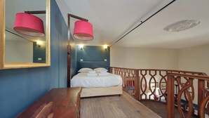 A bedroom with a bed, a wooden desk, a mirror, and a balcony railing. - Studio con Soppalco • Via Gregoriana • Vicino Piazza di Spagna (Rome)