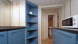 A kitchen with blue cabinets, a white microwave, and a wooden floor. - Studio con Soppalco • Via Gregoriana • Vicino Piazza di Spagna (Rome)