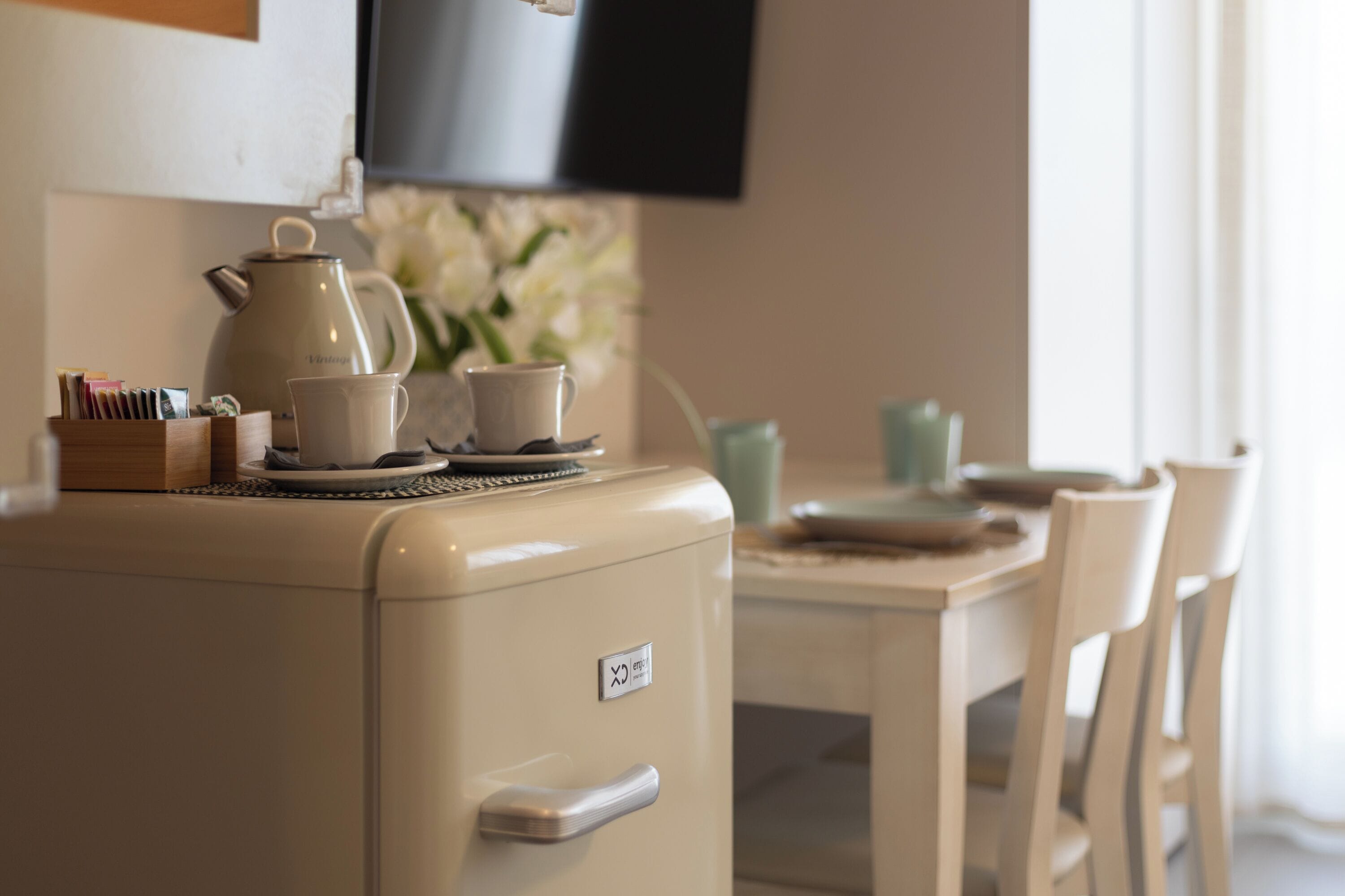 Une petite cuisine équipée d’un réfrigérateur de style rétro, d’une machine à café et d’un service à thé.