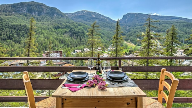 A table set for two with a mountain view, wooden chairs, and a bottle of wine. - Starkeeper Apartment Ski Base With Balcony Views (Pragelato)