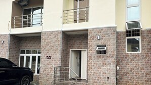 Un edificio di due piani con facciata in mattoni, un balcone al piano superiore e una scalinata che conduce all'ingresso.