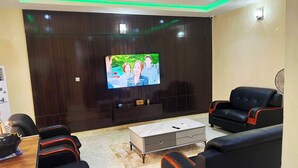 Un soggiorno moderno con una TV a schermo piatto, divani in pelle nera, un tavolino da caffè e un mobile TV in legno scuro.