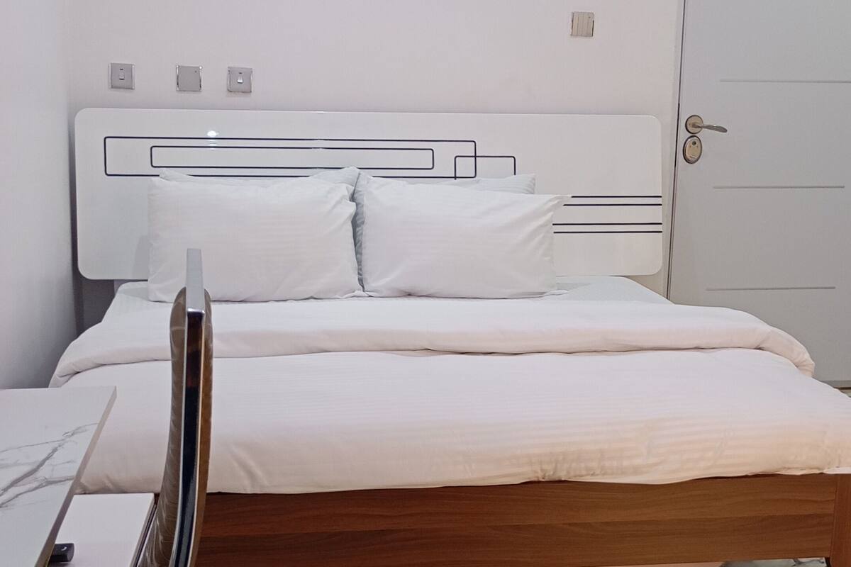 A bedroom with a bed, a desk, and a wardrobe.