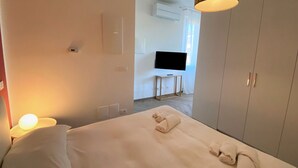 Een hotelkamer met een bed, een televisie, een kledingkast en een lamp.