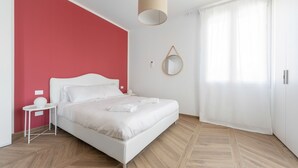 Une chambre à coucher moderne avec un lit, une table de chevet et une lampe suspendue.