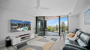 A modern living room with a flat-screen TV, a leather sofa, a coffee table, and a balcony with a pool view. - Solaris 610 overlooking the lake. (Forster)