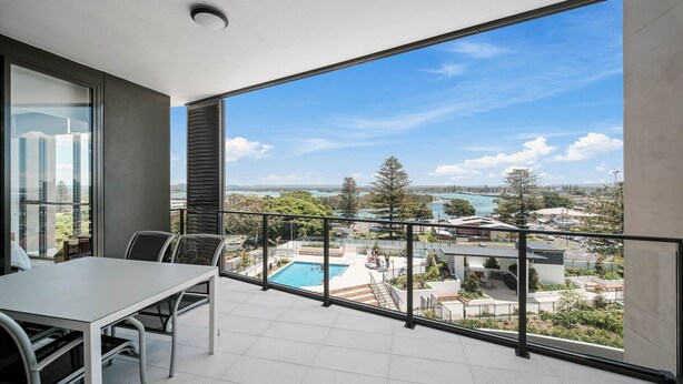 A balcony with a pool view, a dining area, and a clear sky. - Solaris 610 overlooking the lake. (Forster)