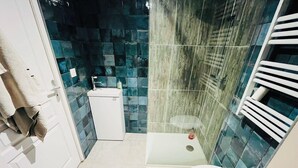 Een kleine badkamer met een wit wastafel, toilet en douche.