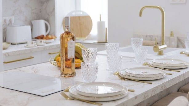Una cocina moderna con encimeras de mármol blanco, accesorios dorados y una salpicadera de mármol.