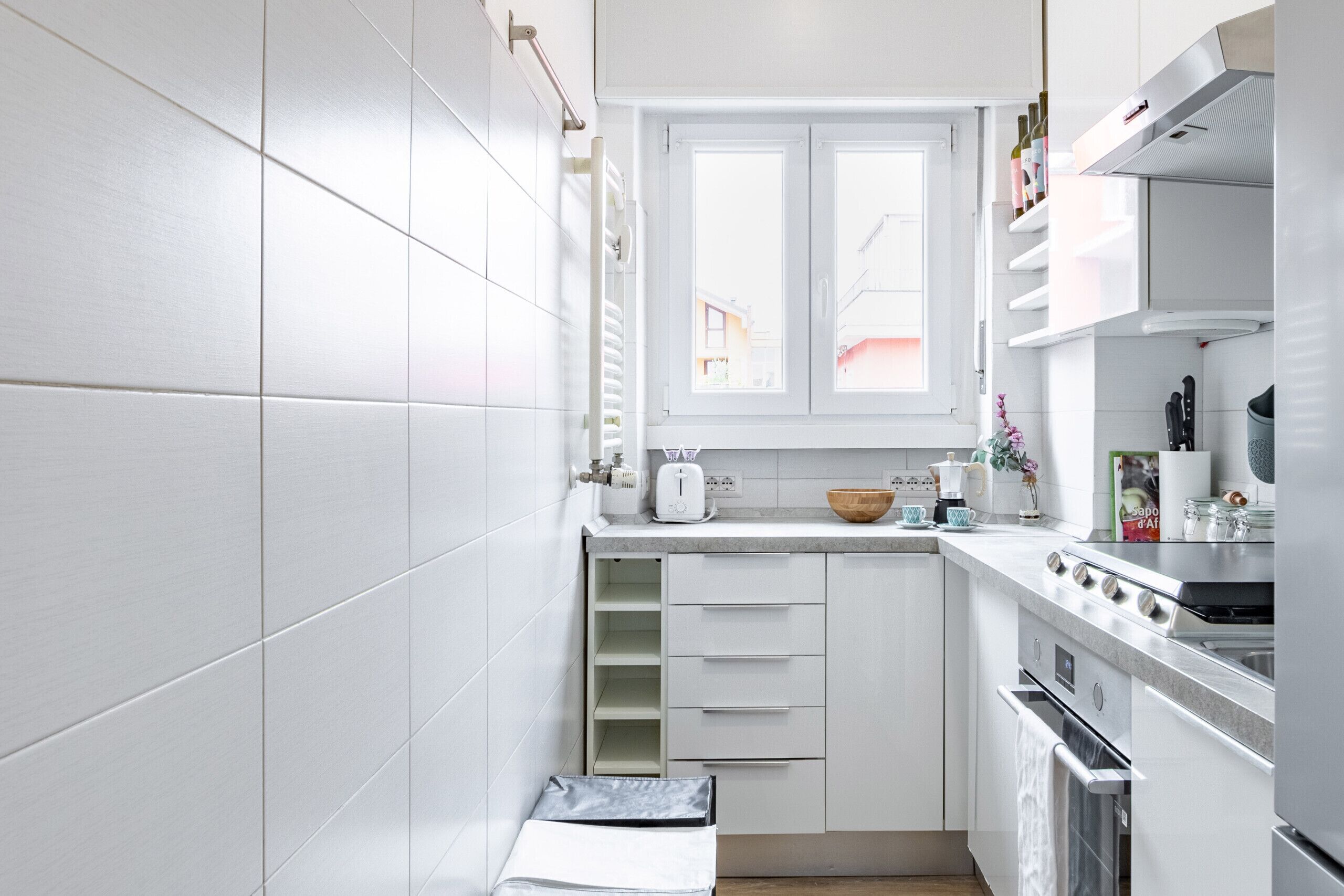 Eine moderne Küche mit weißen Schränken, einem eingebauten Backofen und einem Fenster über der Spüle.