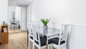 A modern dining area with a glass table, white chairs, and a potted plant. - Golfo Aranci (Milano)