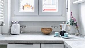 A kitchen with a window, a toaster, a coffee maker, a bowl, and two cups. - Golfo Aranci (Milano)