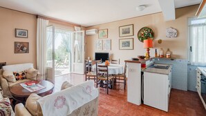 En rummelig opholdsstue med spisebord, stole, sofa og et køkken med vask og skabe.